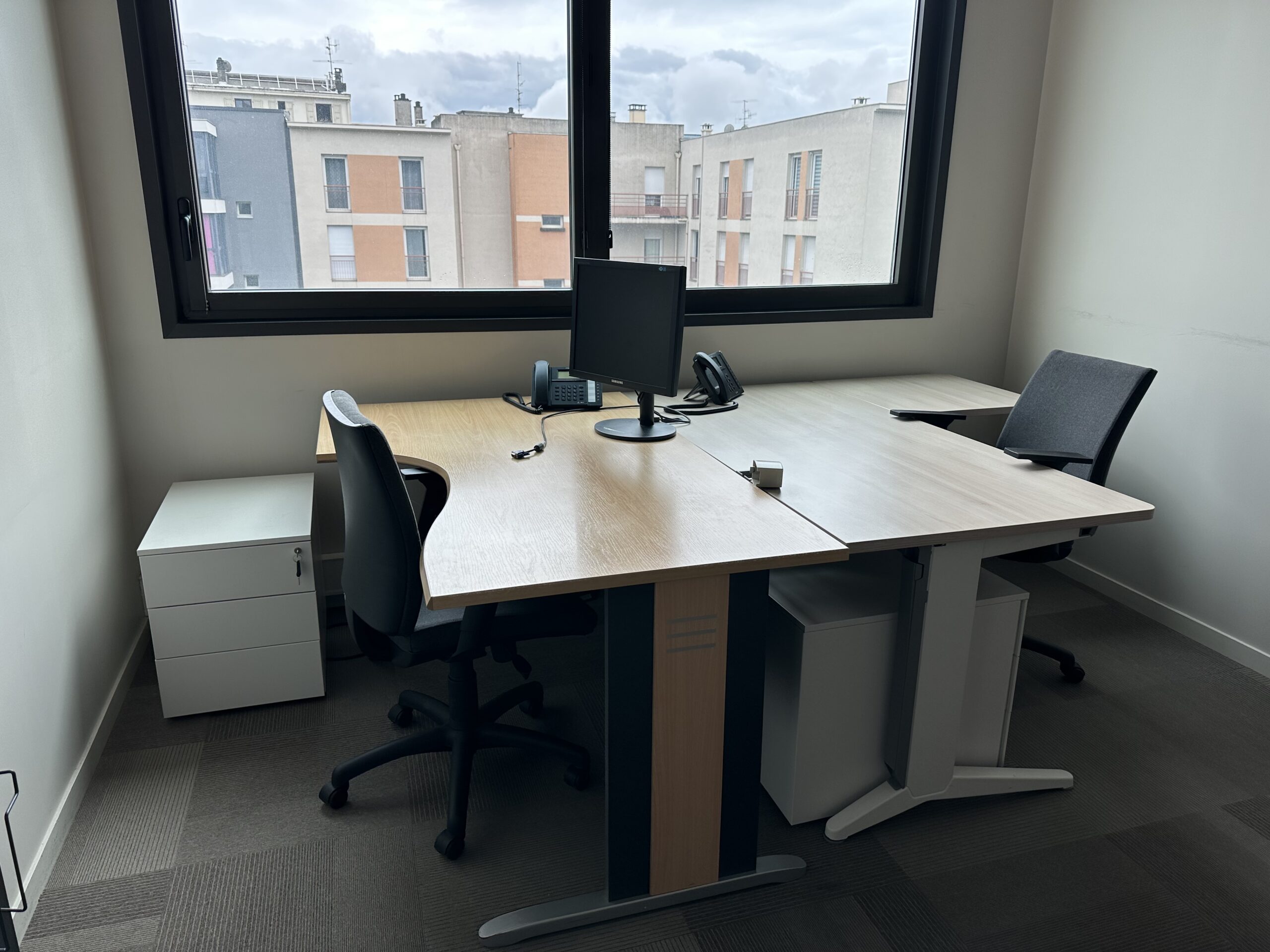 Office workspace with two desks, chairs, and a computer monitor.